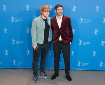 Portrait of happy friends standing against blue background