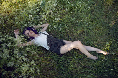 Full length of young woman lying on grassy field