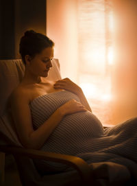 Pregnant woman sitting on chair at home