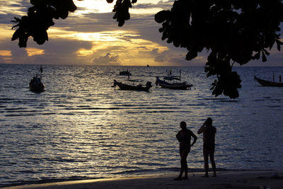 Silhouette of people on beach at sunset