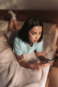 Portrait of young woman sitting on bed at home