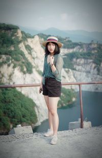 Portrait of beautiful young woman standing on mountain against sky