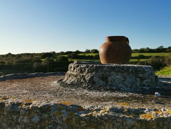 Close-up of jar on rock against blue sky