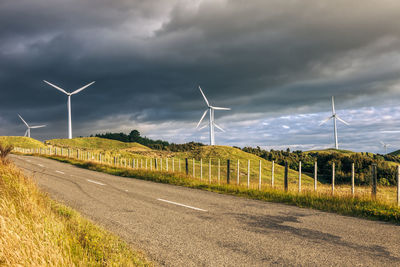 Wind turbines on field against cloudy sky