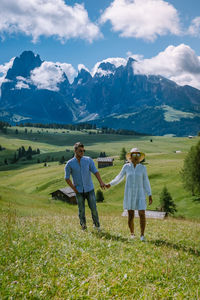 Rear view of men standing on field against mountains