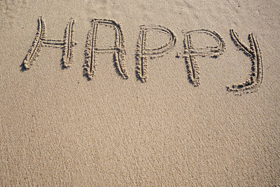 Happy word written on sand. travel summer beach vacation concept