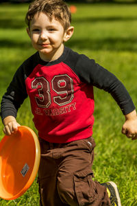 Boy playing with plastic disc on grassy field