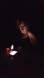 Mature woman using mobile phone in darkroom