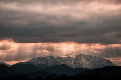 Scenic view of snowcapped mountains against dramatic sky