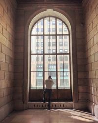 Rear view of man standing against window in building