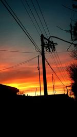 Low angle view of silhouette electricity pylon against sky during sunset