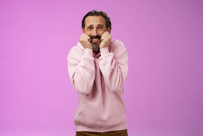 Scared man with hooded shirt against purple background