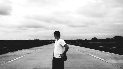 Rear view of man standing on road against sky