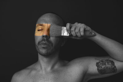 Close-up portrait of shirtless man against black background
