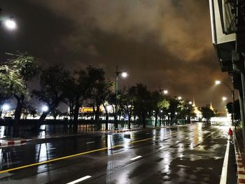 Illuminated street lights on road during rainy season at night