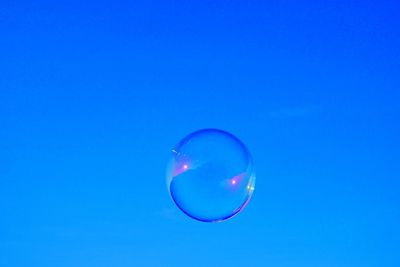 Low angle view of bubbles against blue sky