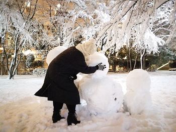 Rear view of woman walking on snow covered tree