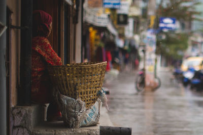 Woman with basket sitting at entrance of house