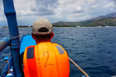 Rear view of man with umbrella on sea against sky