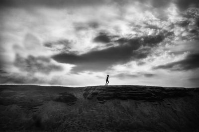 Person standing on rock against sky