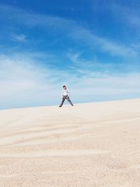 Man standing on sand at desert against sky