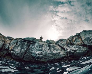 Man standing on rock against sky