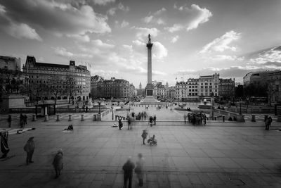 People at trafalgar square against sky in city