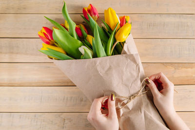 The process of wrapping bouquet of fresh tulips in eco-friendly craft paper. gift for spring holiday