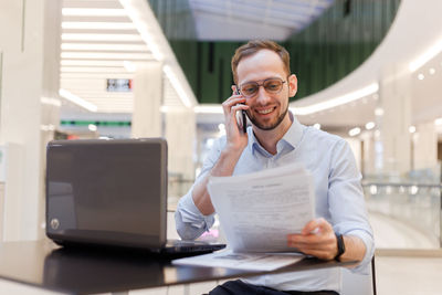 Businessman talking on phone while sitting at mall