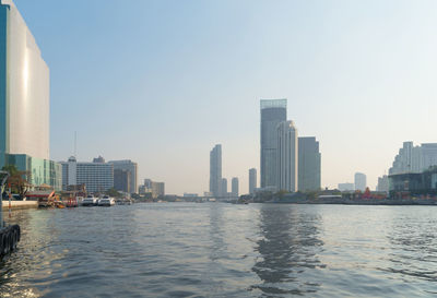 Sea by modern buildings against clear sky