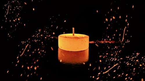 Close-up of illuminated candles against black background