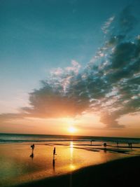 Silhouette people on beach against sky during sunset