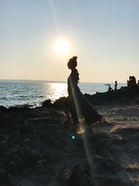 Man on beach against sky during sunset