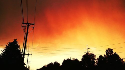 Low angle view of silhouette electricity pylon against sky during sunset