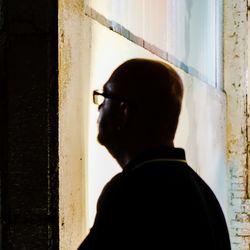 Rear view of man looking through window