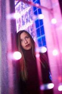 Young woman by illuminated light at night