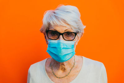 Portrait of smiling woman standing against orange background