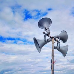 Low angle view of megaphones against cloudy sky