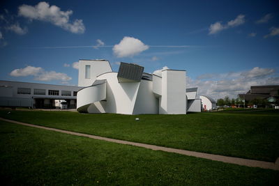 View of field by buildings against sky