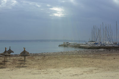 Sailboats moored on beach against sky