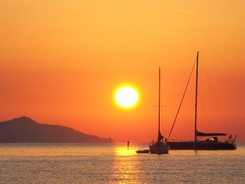 Silhouette sailboats in sea against romantic sky at sunset