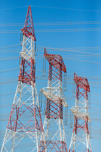 Low angle view of electricity pylon against blue sky