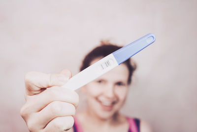 Close-up portrait of woman holding pregnancy kit