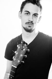 Portrait of man playing guitar against white background