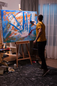 Rear view of man paining at home
