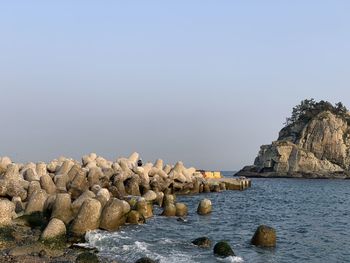 Rocks by sea against clear sky