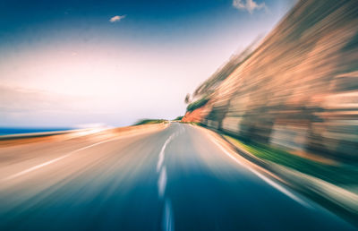 Light trails on road against sky