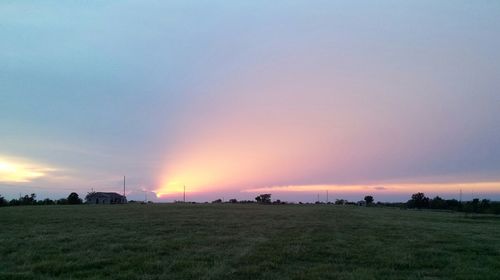 Scenic view of landscape against cloudy sky at sunset