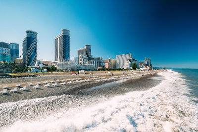 Sea and modern buildings against clear blue sky