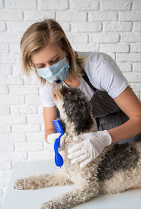 Woman holding dog against wall